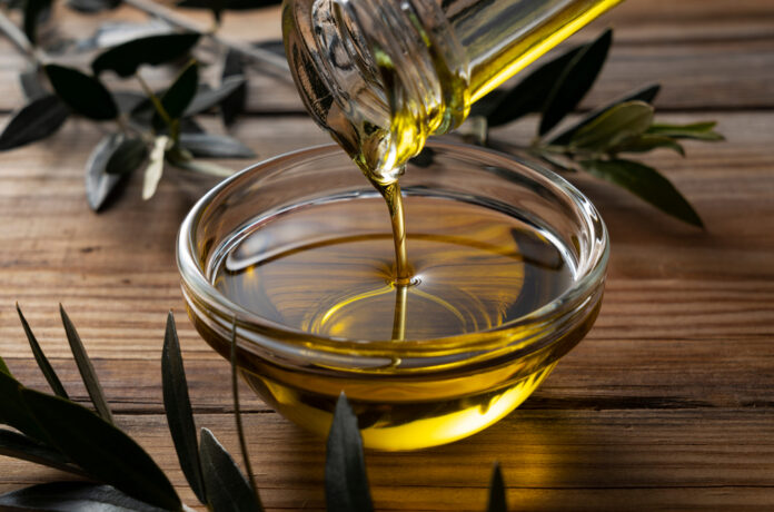 The,Moment,Olive,Oil,Is,Poured,Into,A,Glass,Bowl olio di oliva extravergine